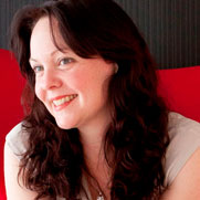 Profile shot of Amanda Bridgeman sitting on a red chair.