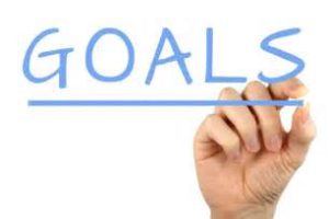 A person's hand writing the word 'goals'